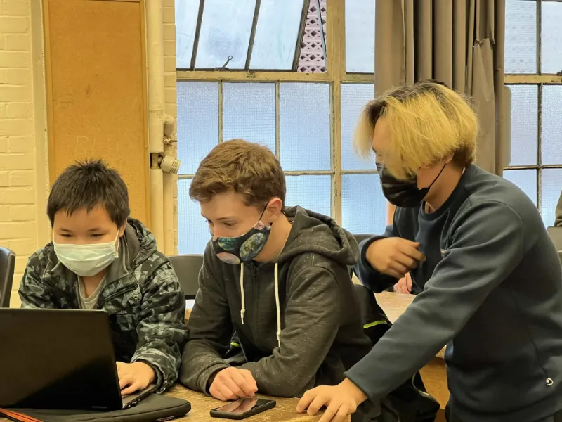 Isaac, Jacob and another member working around a laptop